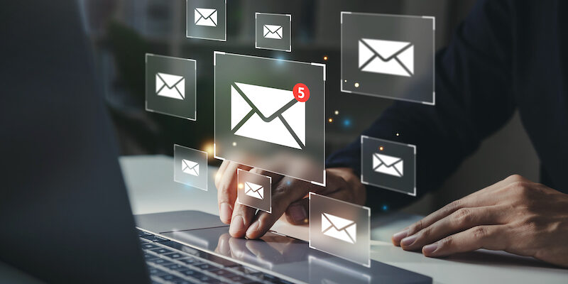 Businessman using laptop with email notification alert on virtual screen.